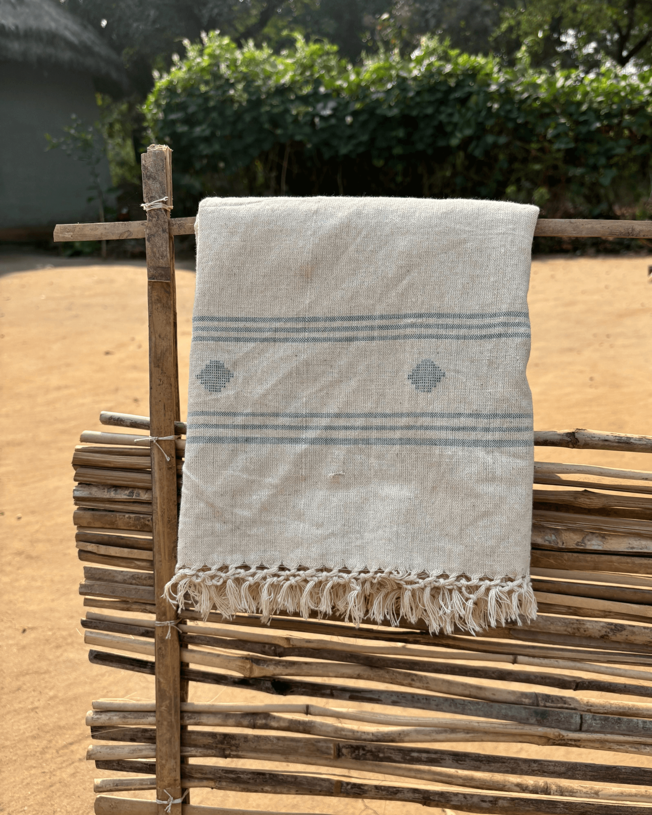 Handwoven Jamdani Dopatta with natural dyes, showcasing intricate design on rustic wooden stand.